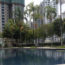 Picture of a pool surrounded by palm trees and tall apartment buildings with white text saying "A year of housesitting in SE Asia"