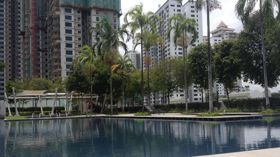 Picture of a pool surrounded by palm trees and tall apartment buildings with white text saying "A year of housesitting in SE Asia"