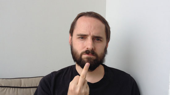 Picture of a white male in a black shirt holding his middle finger up to the camera