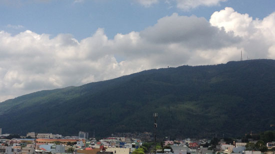 Picture of Quy Nhon, Vietnam with mountains and clouds in the background and city buildings in the foreground.