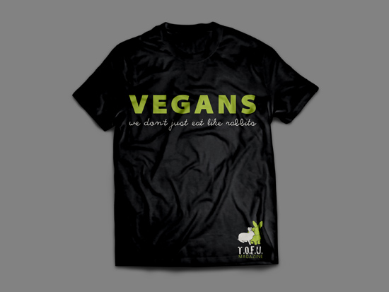 Picture of a black shirt against a grey background. The shirt has green text that says "Vegans" and white text below that says "We don't just eat like rabbits". In the bottom of the shirt, there are two small rabbits just above the words "T.O.F.U. Magazine"