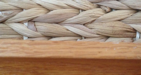 Image contains a wicker basket on top of a wooden shelf.