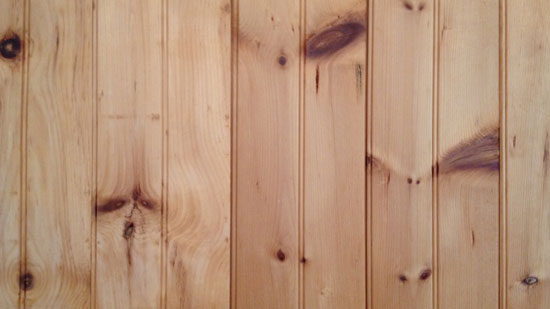 Image contains vertical wood panelling with a number of darker brown knots scattered throughout each panel.