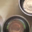 Image contains four silver dog bowls from a birds-eye view. The bowls are on an off-white countertop.