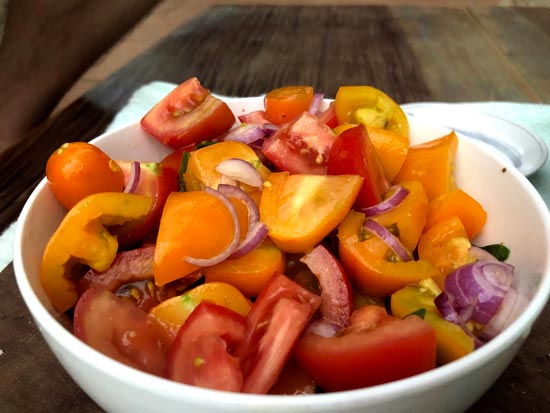 Image contains a photo of a bowl of chopped tomatoes with red onion, basil, chili flakes, oil, and vinegar.