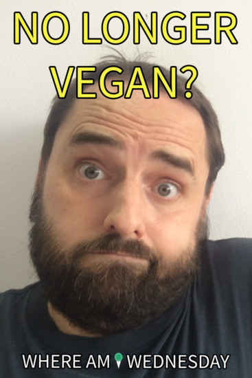 Image contains a photo of a bearded man with a questioning look on his face and his shoulder raised. Above his head, there is yellow text that says "No Longer Vegan?" Below him, there is white text that says "Where Am I Wednesday".