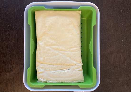 Block of firm tofu placed in the Tofuture tofu press.